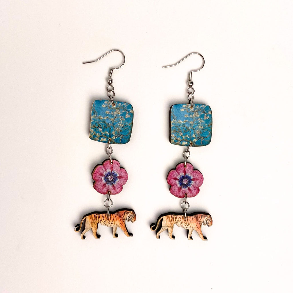 Earrings with blue square pendants, pink floral charms, and tiger figures on a white background